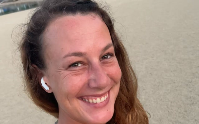 Sarah smiling on the beach at sunset